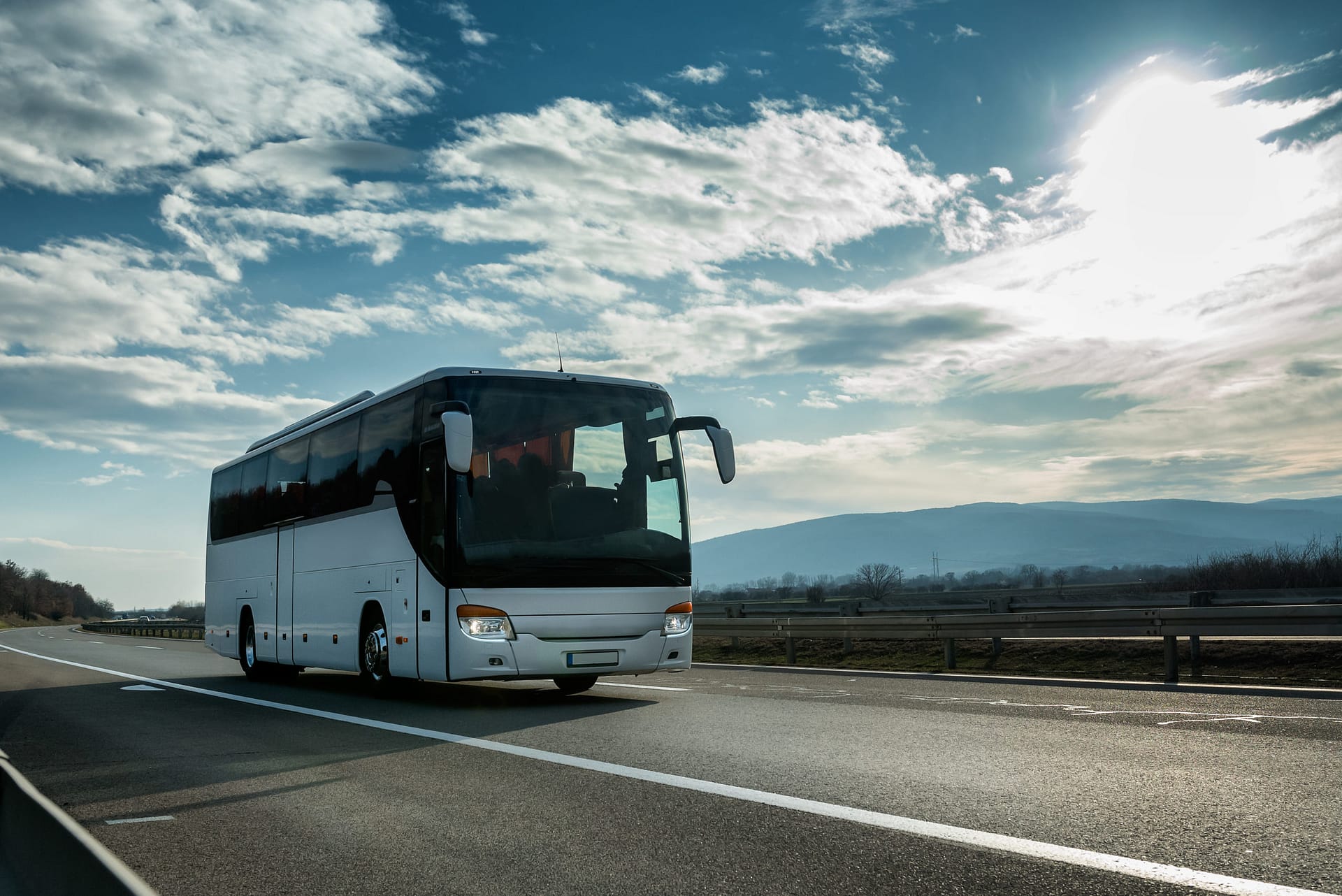 Bus touristique confortable et moderne blanc traversant l'autoroute à